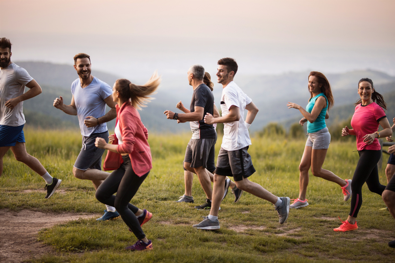 Large group of sports people running through nature and communicating.